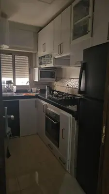 a kitchen with white cabinets and a black stove top oven at Appartement proche de la mer de bouznika in Bouznika