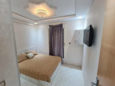 a small bedroom with a bed and a television at Appartement perle de bouznika in Kasba Bou Hamira