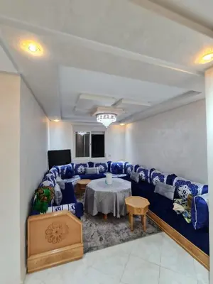 a living room with a blue couch and a table at Appartement perle de bouznika in Kasba Bou Hamira
