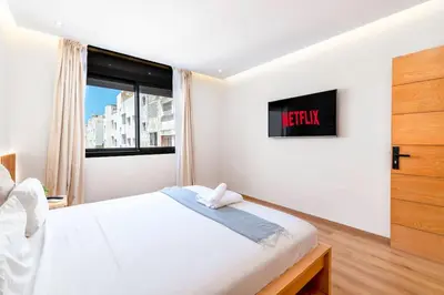 a white bedroom with a bed and a tv at Modern and Luxurious apartment in Rabat