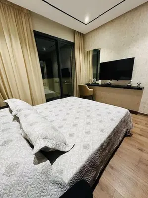 a bedroom with a large bed and a television at Studio Al Amir 12 CFC à 2mn in Casablanca