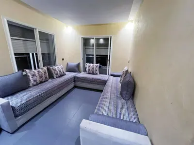 a living room with a couch and two windows at Les perles de tamaris in Dar Mohammed Ould Haj Jilali