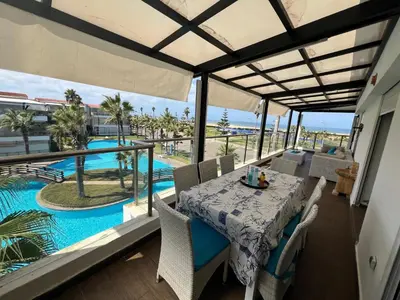 a dining room with a table and a view of a pool at Les perles de tamaris in Dar Mohammed Ould Haj Jilali