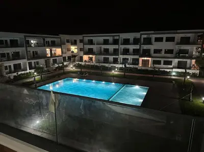 a swimming pool in front of a building at night at Studio Cosy avec Vue Piscine El Mansouria in Mansouria