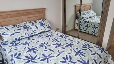 a bedroom with a bed with a blue and white comforter at Bel Appartement avec Piscine et Jardin, EL MANSOURIA in Mansouria