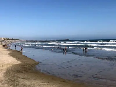 a group of people standing in the water at the beach at Bel Appartement avec Piscine et Jardin, EL MANSOURIA in Mansouria