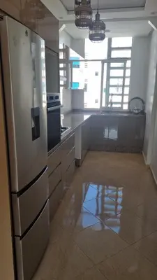 a kitchen with a stainless steel refrigerator in a room at Bel Appartement avec Piscine et Jardin, EL MANSOURIA in Mansouria