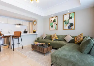 a living room with a green couch and a kitchen at Les Tours Végétales, Casablanca Finance City in Casablanca