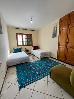 a room with two beds and a rug on the floor at surf trip in Kasba Bou Hamira