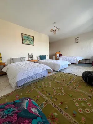 a bedroom with two beds and a rug on the floor at surf trip in Kasba Bou Hamira