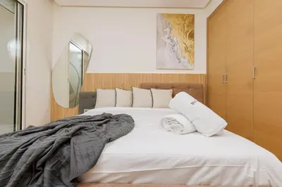 a bedroom with a large bed with white sheets and pillows at Elegant 2BR in Hay Riad - New Furnishings & Design in Beni Brour