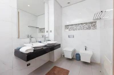 a white bathroom with two sinks and a toilet at Elegant 2BR in Hay Riad - New Furnishings & Design in Beni Brour