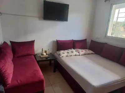 a living room with a couch and a tv on the wall at vague bleue de bouznika in Bouznika