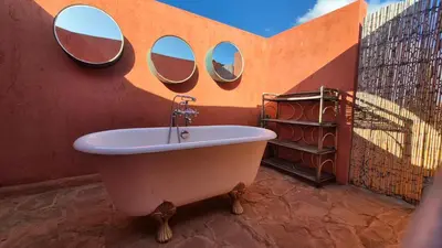 a bathroom with a tub with three mirrors on the wall at Kasbah Oum Rabia in Boulaouane