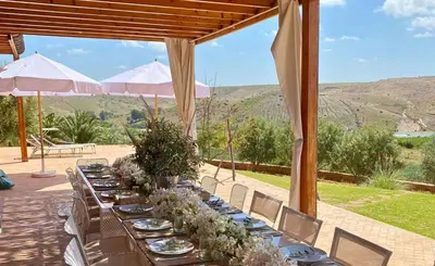 a long table with white plates and flowers on it at Kasbah Oum Rabia in Boulaouane