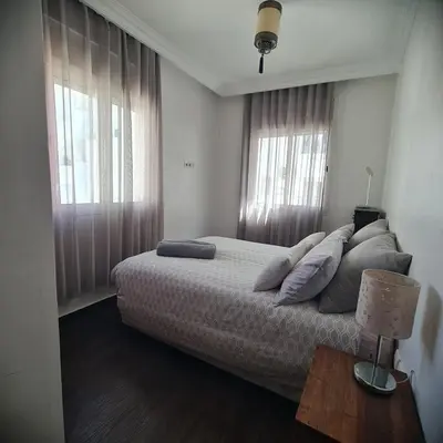 a bedroom with a bed and two windows at Appartement confortable et bien situé in Casablanca