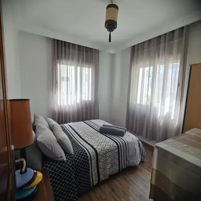 a bedroom with a bed and two windows at Appartement confortable et bien situé in Casablanca