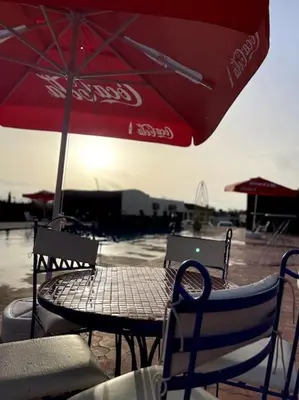 a table and chairs with a red umbrella at Jnane Jawhara Skhirat studio in Skhirat