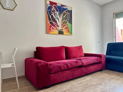 a red couch in a living room with a painting at Cosy and practical apartment in Maarif