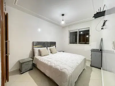 a white bedroom with a bed and a window at Charmant appt 2 ch terrasse in Rabat