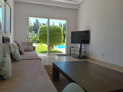 a living room with a couch and a flat screen tv at Superbe villa à Bouznika in Bouznika
