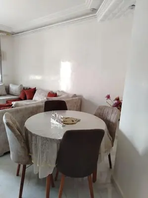 a living room with a table and a couch at Joli Apparemment et calme in Casablanca
