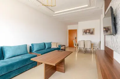 a living room with a blue couch and a table at Residence GYA Beach - Luxe Moderne et Confort à Harhoura accès plage in Temara