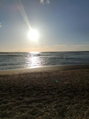 a beach with the sun rising over the ocean at Appartement Confortable en Résidence Privée avec Piscine in Pont Blondin