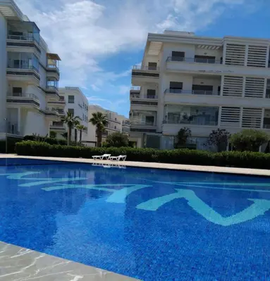 a swimming pool in front of two apartment buildings at Appartement Confortable en Résidence Privée avec Piscine in Pont Blondin
