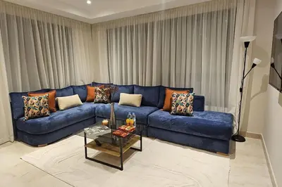 a living room with a blue couch and a table at Emplacement Central & So Stylish Près du Consulat Américain 2 minutes de Twin Center Gauthier Casablanca in Casablanca