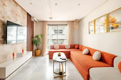 a living room with an orange couch and a table at AS140 élégant coeur de Casablanca avec Wifi Parking et Tramway in Casablanca