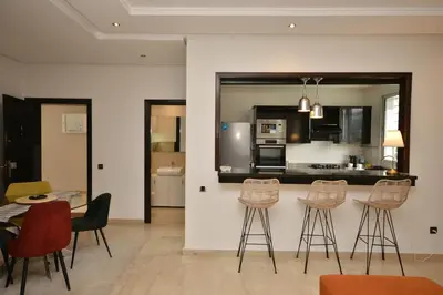a kitchen with a bar with stools and a table at Lovely 2 bedroom flat in Ain Diab in Casablanca