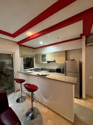 a kitchen with two red bar stools in a room at Votre chez-vous à Casa, une ambiance cosy garantie in Casablanca