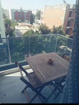 a wooden table and chair on a balcony at Maarif dar zara 2 chambres ,Wifi ,Parking Gratuit in Casablanca