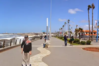 a woman walking down a sidewalk next to the beach at Maarif dar zara 2 chambres ,Wifi ,Parking Gratuit in Casablanca