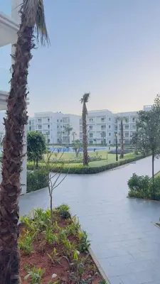 a palm tree in a park with a building at Cosy Suite Appart in Bouznika