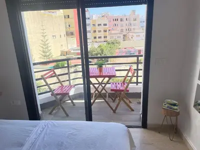 a bedroom with a balcony with a table and chairs at Joli cocon en plein centre a10 min a pieds de la corniche in Casablanca