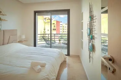 a white bedroom with a bed and a balcony at Joli cocon en plein centre a10 min a pieds de la corniche in Casablanca