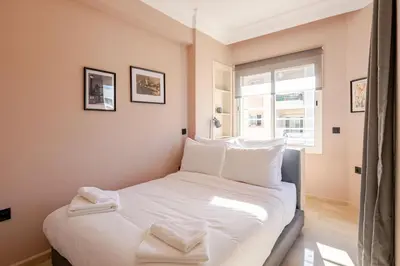 a bedroom with a bed with white sheets and a window at The 23 Princesses by IB Signature - Stylish 2 Bedroom Apt with Wifi, Self check-in - 24 x7 Security - City View - Walk to Cafes! City Centre in Casablanca
