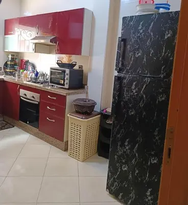 a kitchen with a black refrigerator and red cabinets at appartement calme in Casablanca