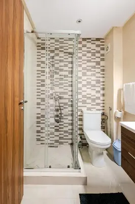 a bathroom with a shower with a toilet and a sink at Appartement luxueux avec piscine dans une résidence calme in Bouznika