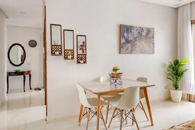 a dining room with a table and white chairs at Appartement luxueux avec piscine dans une résidence calme in Bouznika