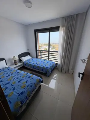 a bedroom with two beds and a balcony at Appartement luxueux avec piscine dans une résidence calme in Bouznika