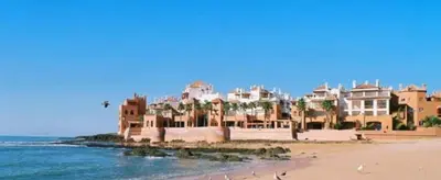 a group of houses on a beach next to the ocean at Appartement luxueux avec piscine dans une résidence calme in Bouznika