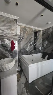 a bathroom with a white tub and a marble wall at Marina casablanca in Casablanca