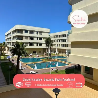 a hotel with a swimming pool in front of a building at Garden Paradise Bouznika Beach Apartment in Bouznika
