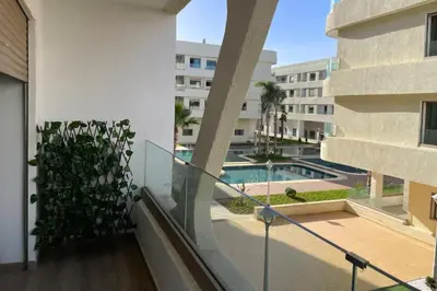 a balcony of a building with a swimming pool at Garden Paradise Bouznika Beach Apartment in Bouznika