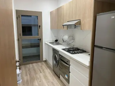 a small kitchen with a stove and a refrigerator at Garden Paradise Bouznika Beach Apartment in Bouznika