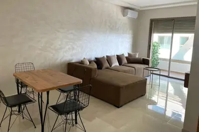 a living room with a couch and a table and chairs at Garden Paradise Bouznika Beach Apartment in Bouznika