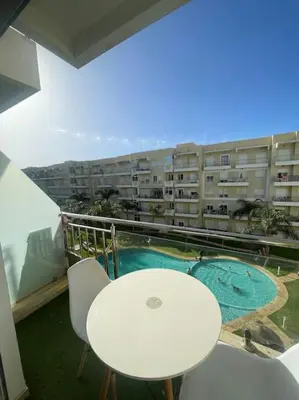 a balcony with a table and chairs and a building at Appart avec Piscine Proche de la Mer in Bouznika